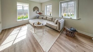 Ein Wohnzimmer mit einer Eckcouch, einem runden Couchtisch und einem gewebten Korb.