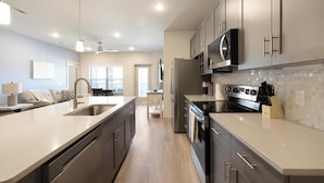 Una cocina moderna con electrodomésticos de acero inoxidable, una isla central y vistas al área de estar.