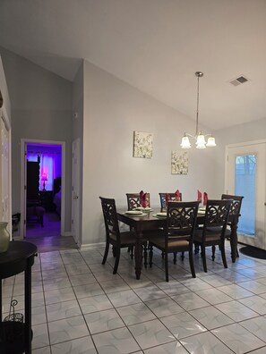 A dining area with a table set for four, a chandelier, and two wall-mounted artworks.