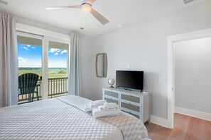 A bedroom with a bed, a television, a globe, and a view of the outdoors through a sliding door. - New Build! Salt Marsh views in the heart of Surf City. Walk anywhere! (Surf City)