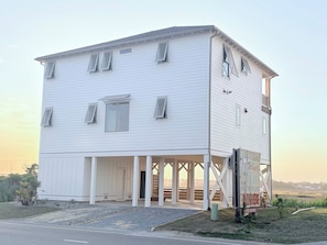 A white building with a covered porch and a signboard. - New Build! Salt Marsh views in the heart of Surf City. Walk anywhere! (Surf City)