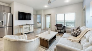 A modern living room with a sofa, armchair, coffee table, and a TV. - Landing | Modern 2BD, Clubhouse, Game Room (Mansfield)