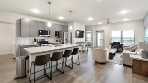 Een moderne keuken met een centraal eiland, barkrukken en een eethoek met een bank en tafel.