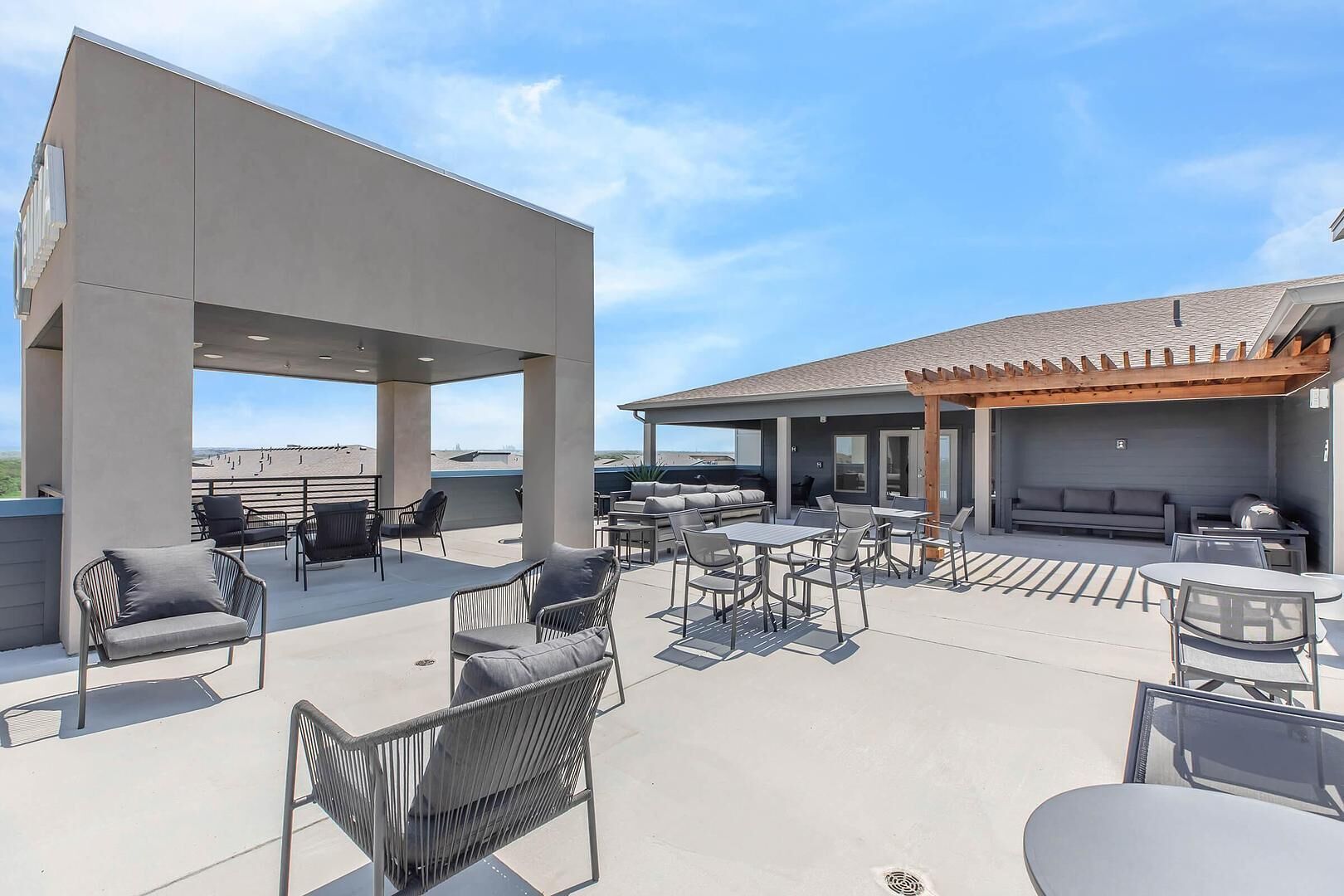 A rooftop patio with outdoor seating, a pergola, and a barbecue area.
