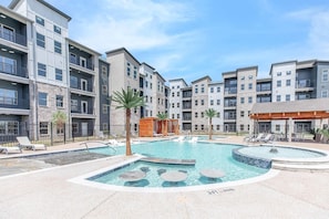 Ein modernes Apartmenthaus mit einem zentral gelegenen Schwimmbad, Liegestühlen und einer kleinen Whirlpool-Anlage.