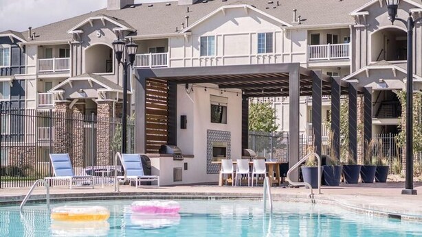 Une piscine avec des chaises longues et un espace barbecue.