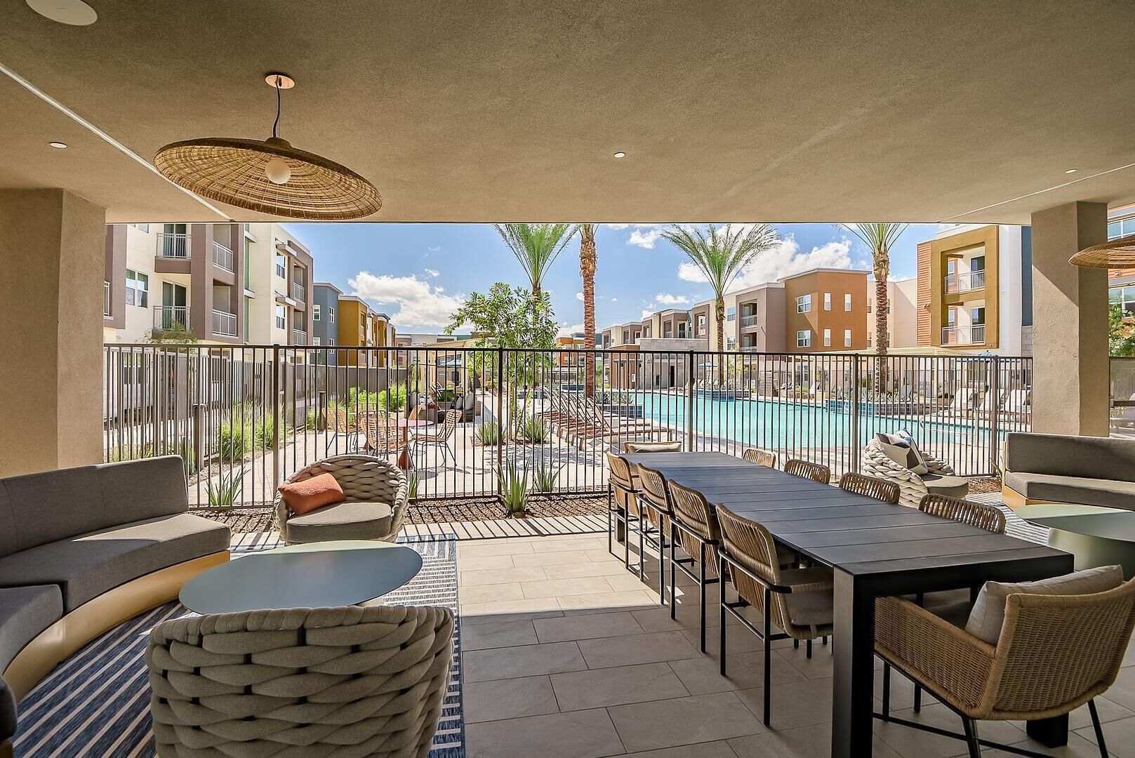 En udendørs terrasse med swimmingpool, siddepladser og udsigt til omkringliggende bygninger.
