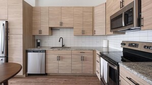 Une cuisine moderne avec des meubles en bois, un réfrigérateur en acier inoxydable, un lave-vaisselle, un four à micro-ondes et un four traditionnel.