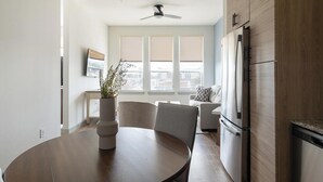 Une cuisine moderne équipée d’une table à manger, de chaises, d’un réfrigérateur et d’un ventilateur de plafond.