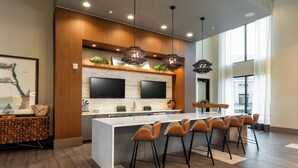 Una cucina moderna con isola centrale, sgabelli da bar e illuminazione a sospensione.