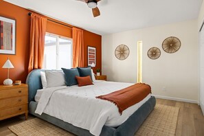 Une chambre à coucher comprenant un lit, des tables de chevet, un ventilateur de plafond et des éléments de décoration murale.