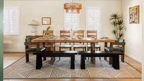 Comedor con una mesa rectangular, seis sillas, una lámpara colgante y un tapete estampado.