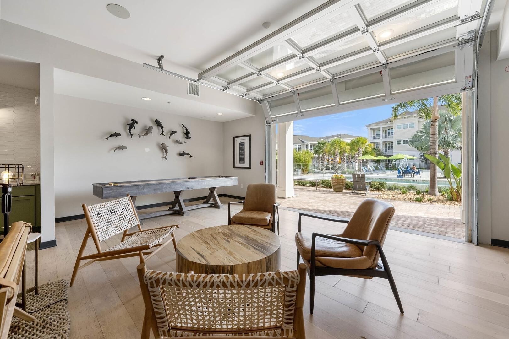 A modern interior with a pool table, wicker chairs, and a view of the pool area.
