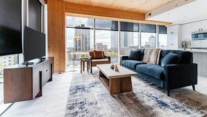 Una sala de estar moderna con un televisor grande, techo de madera y vistas a la ciudad.
