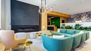 A modern living room with a fireplace, green sofas, and a coffee table. - Landing | Amazing 3BD, Pool, Game Room (Milwaukee)
