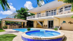 Ein zweigeschossiges Haus mit Schwimmbad, überdachter Terrasse und Balkon.