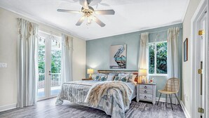Ein Schlafzimmer mit einem Bett, Nachttischen, einem Sessel und einem Deckenventilator.