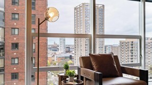Een moderne woonkamer met een leren bank, een klein rond tafeltje met een plant en een vloerlamp.
