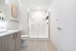 Een moderne badkamer met douche, toilet en wastafel.