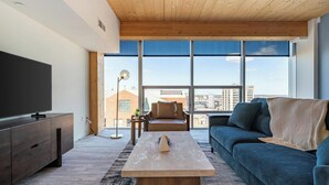 Un salon moderne avec un téléviseur à écran plat, un canapé, une table basse et un lampadaire.