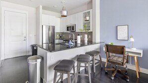 A modern kitchen with a central island, stainless steel appliances, and bar stools. - Landing | Spectacular 1BD, Gym, Clubhouse (Dallas)