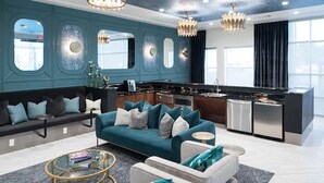 Ein modernes Wohnzimmer mit einer Couch, Sesseln, einem Couchtisch und einer Küchenzeile mit Spüle und Schränken.