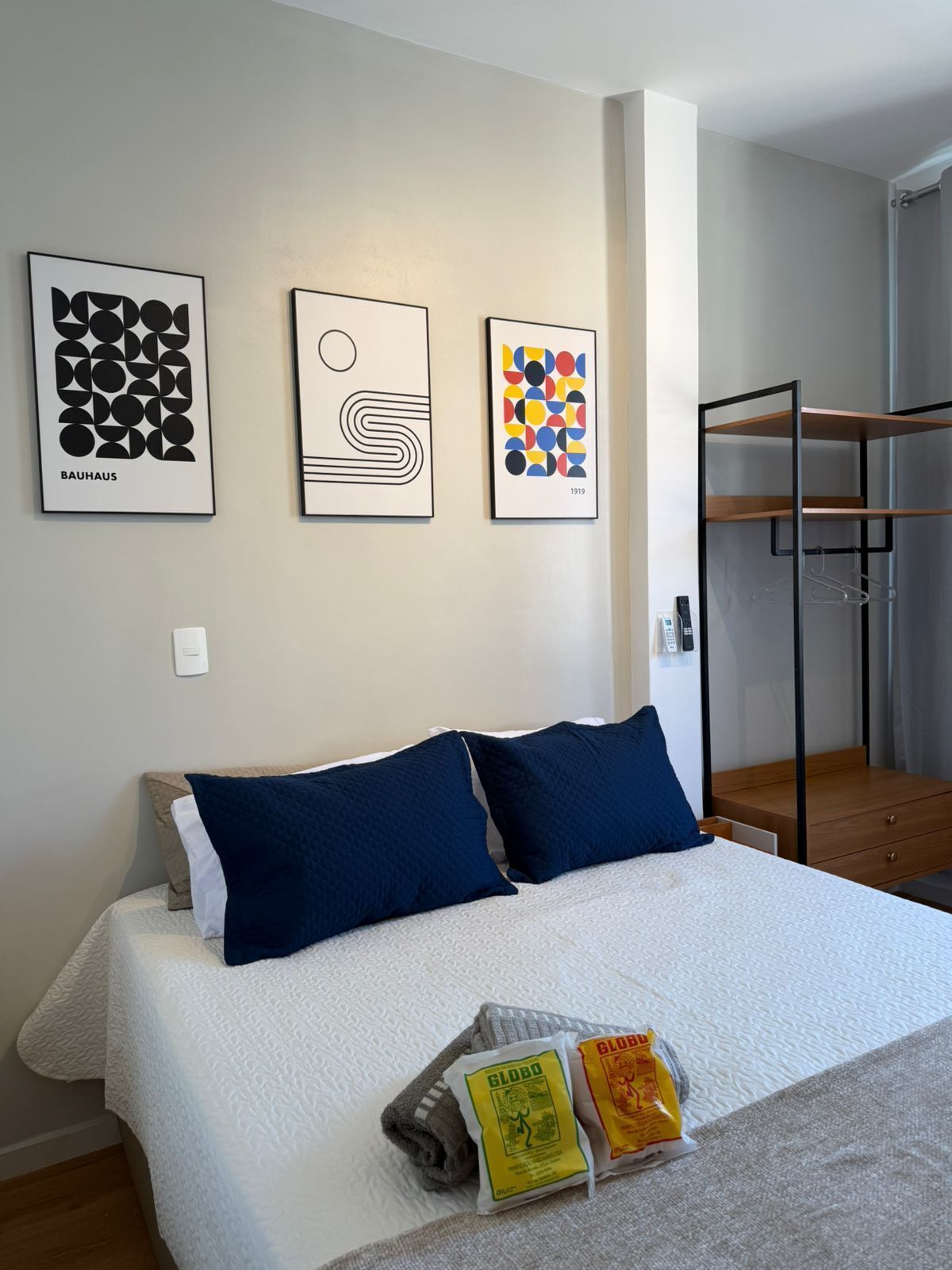 A hotel room with a bed, a bunk bed, and three framed artworks on the wall.