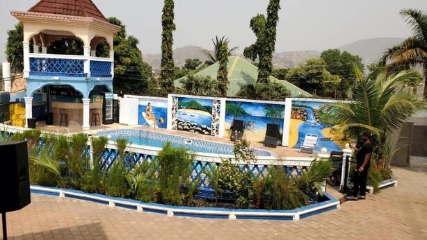 Un área de piscina con un mural, un pabellón y vistas del paisaje circundante.