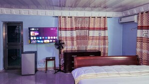 Una habitación con una cama, televisión, aire acondicionado y un escritorio con computadora.