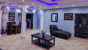 Amplia sala de estar con comedor, un globo terráqueo sobre una mesa y un sofá de cuero negro.
