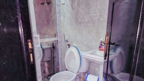 Un baño con inodoro, lavamanos y zona de ducha.