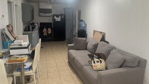 Een ruimtelijk ingerichte leefruimte met een kitchenette, een bank en een eethoek.