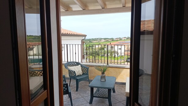 Un balcon avec une chaise, une petite table et un pot de fleurs.