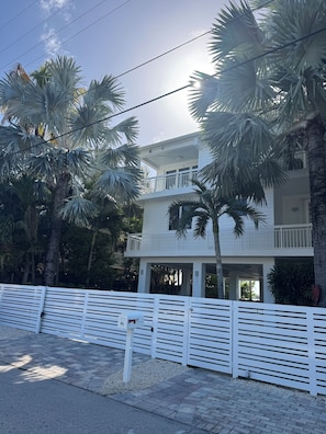 A two-story building with a balcony, surrounded by palm trees. - Bayfront Serenity. 4 En-Suite Bedrooms. 1/2 bath. Elevator. Pool. Private Dock (Tavernier)