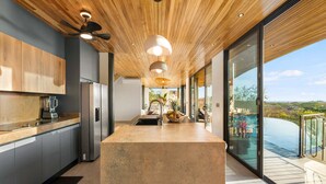 Una cocina moderna con una isla central, techo de madera y amplios ventanales con vistas panorámicas.