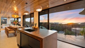 Una cocina moderna con una isla grande, techo de madera y ventanas amplias que ofrecen vistas a la ciudad.