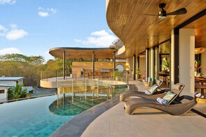A modern outdoor pool area with lounge chairs, a wooden ceiling, and a view of the surrounding landscape. - Brand-New Luxury Villa | Private Pool | Ocean Views | Heart of Tamarindo (Tamarindo)