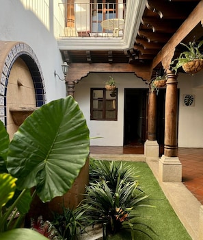 A courtyard with a wooden balcony, a tiled archway, and potted plants. - CASA DON PANCHO Beautiful, fully furnished house (Ciudad Vieja)