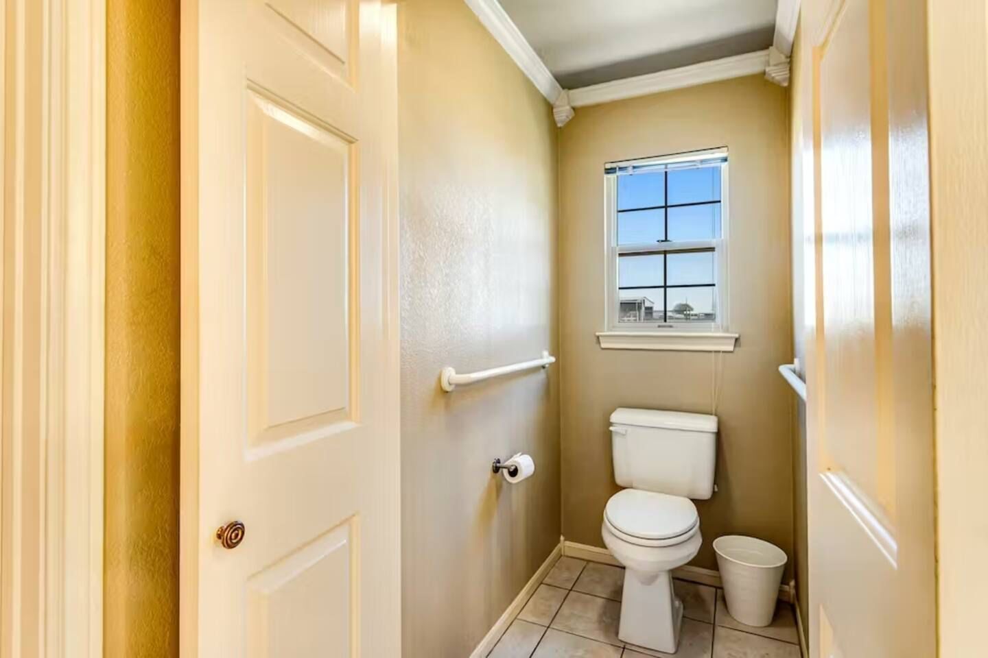 A small bathroom with a toilet, a window, and a door.