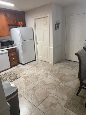 A kitchen with a refrigerator, microwave, and cabinets.