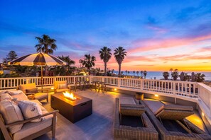 A rooftop terrace with outdoor seating, a fire pit, and a view of the ocean at sunset. - Coastal La Jolla Getaway w/ Panoramic Ocean Views & Private Rooftop (La Jolla)