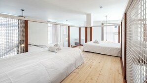 A hotel room with two beds, wooden flooring, and a view through a mesh window. - The Happy House - Welkeys (Saint-Georges-d'Oléron)