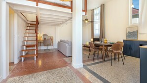 A spacious loft-style room with a wooden staircase, a dining area, and a kitchen. - The Happy House - Welkeys (Saint-Georges-d'Oléron)