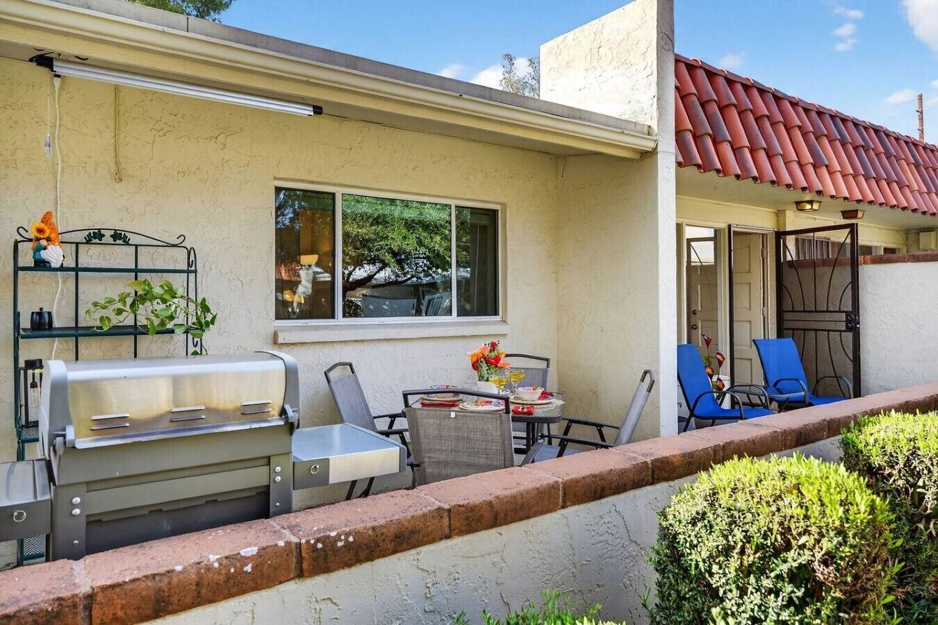 Un patio con una parrilla, asientos al aire libre y vistas de la casa.