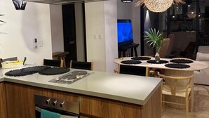 Une cuisine moderne dotée d’un îlot central, de meubles en bois et d’une hotte de cuisine en acier inoxydable.
