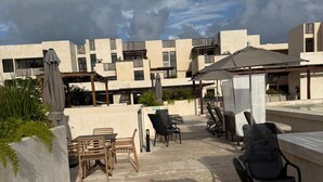 Une terrasse sur le toit avec des espaces de détente en plein air, une piscine et une vue sur des bâtiments modernes.