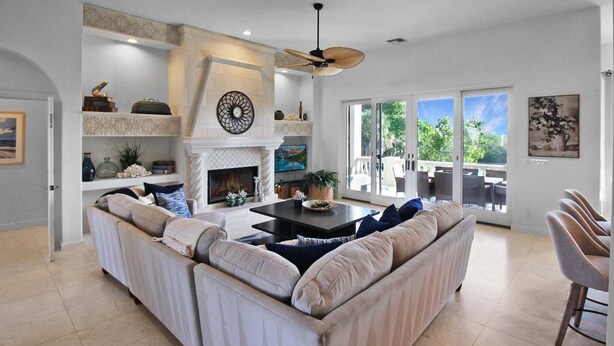 A spacious living area with a fireplace, a sofa set, a dining table, and a view through large sliding doors. - Waterfront Neo Mediterranean Home On Casey Key - Tidewater Manor (Nokomis)