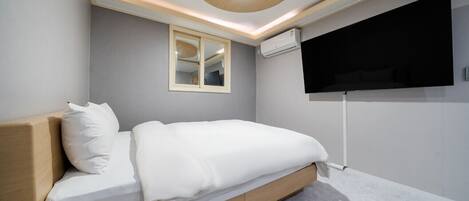 A modern bedroom with a bed, a wall-mounted TV, and a ceiling light fixture.