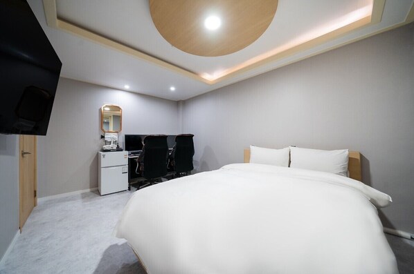 A modern bedroom with a large bed, a desk with a chair, a mirror, and a television. - SOO HOTEL (Seoul)