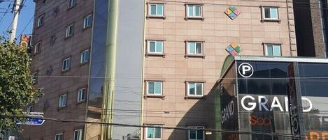 A hotel with a prominent cross on top, a modern glass facade, and a visible parking sign.